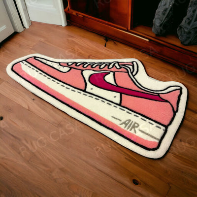 A pink shoe rug featuring an illustration of a Nike Dunk sneaker with a visible swoosh and the text 'AIR' on the sole.